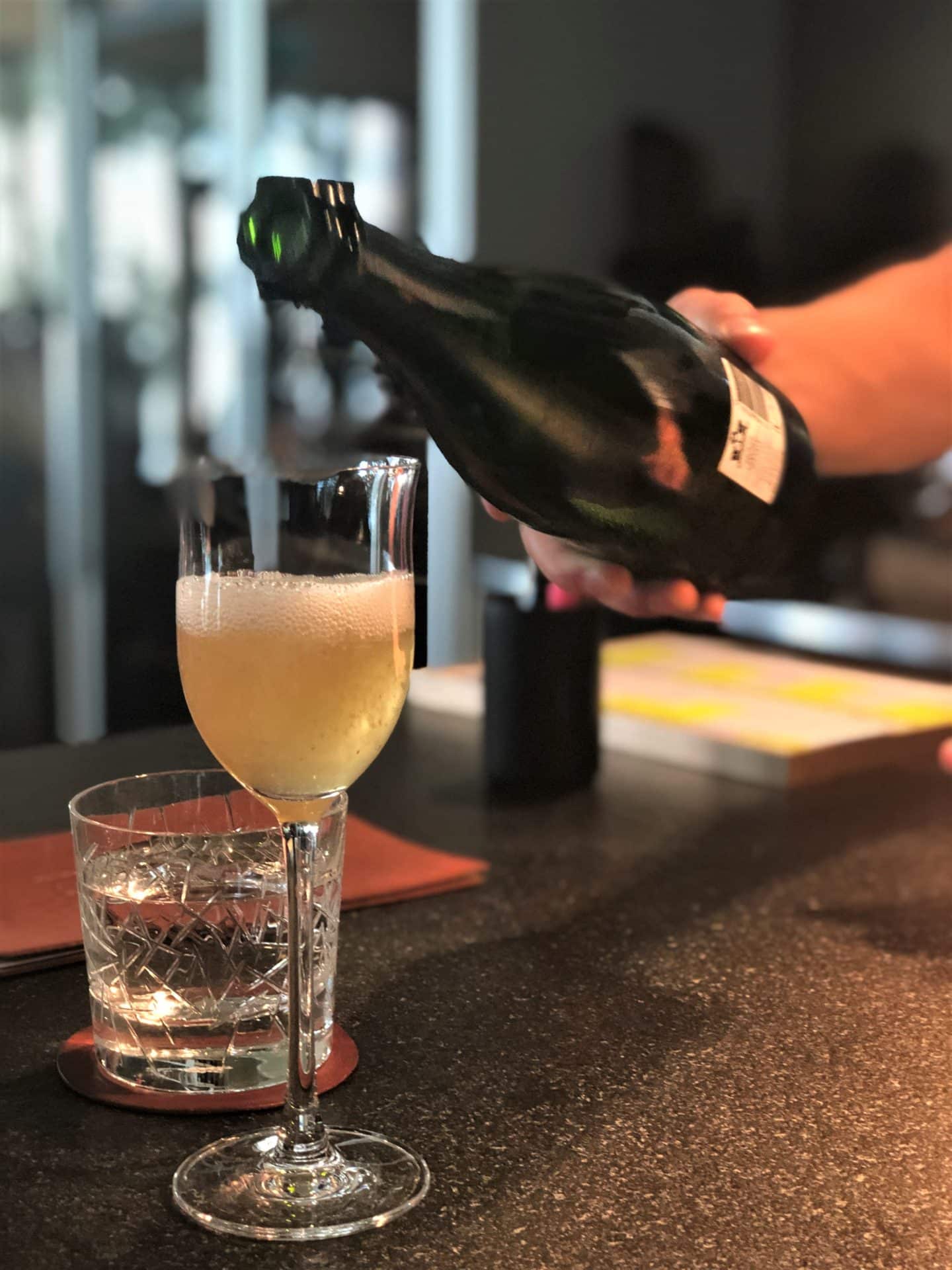 Sparkling dessert wine being poured into a glass from a black bottle at Noa Chef's Hall Tallinn