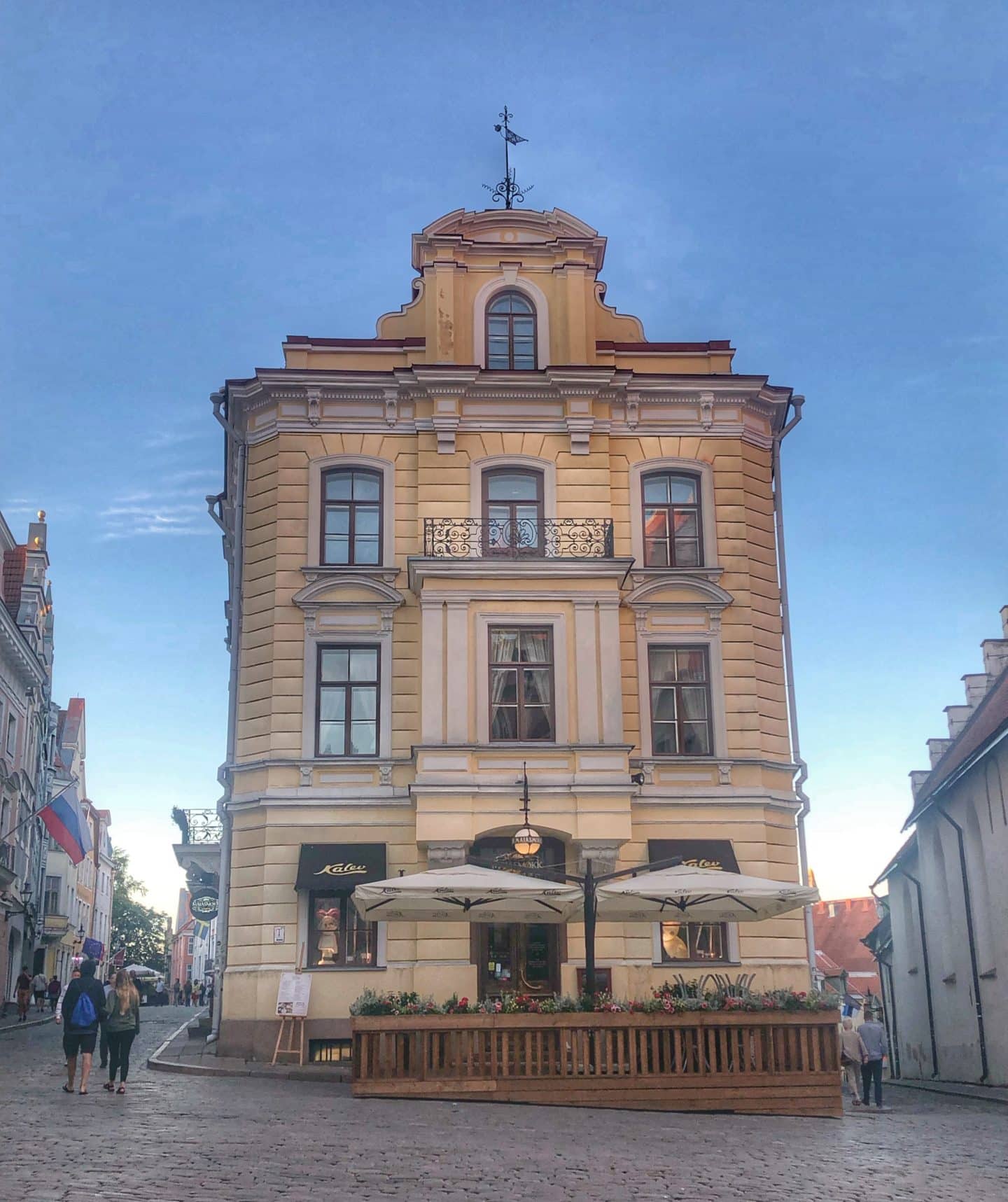 The exterior building of the Maiasmokk cafe in old town Tallinn, There is eating outside with umbrellas to shield from the sun