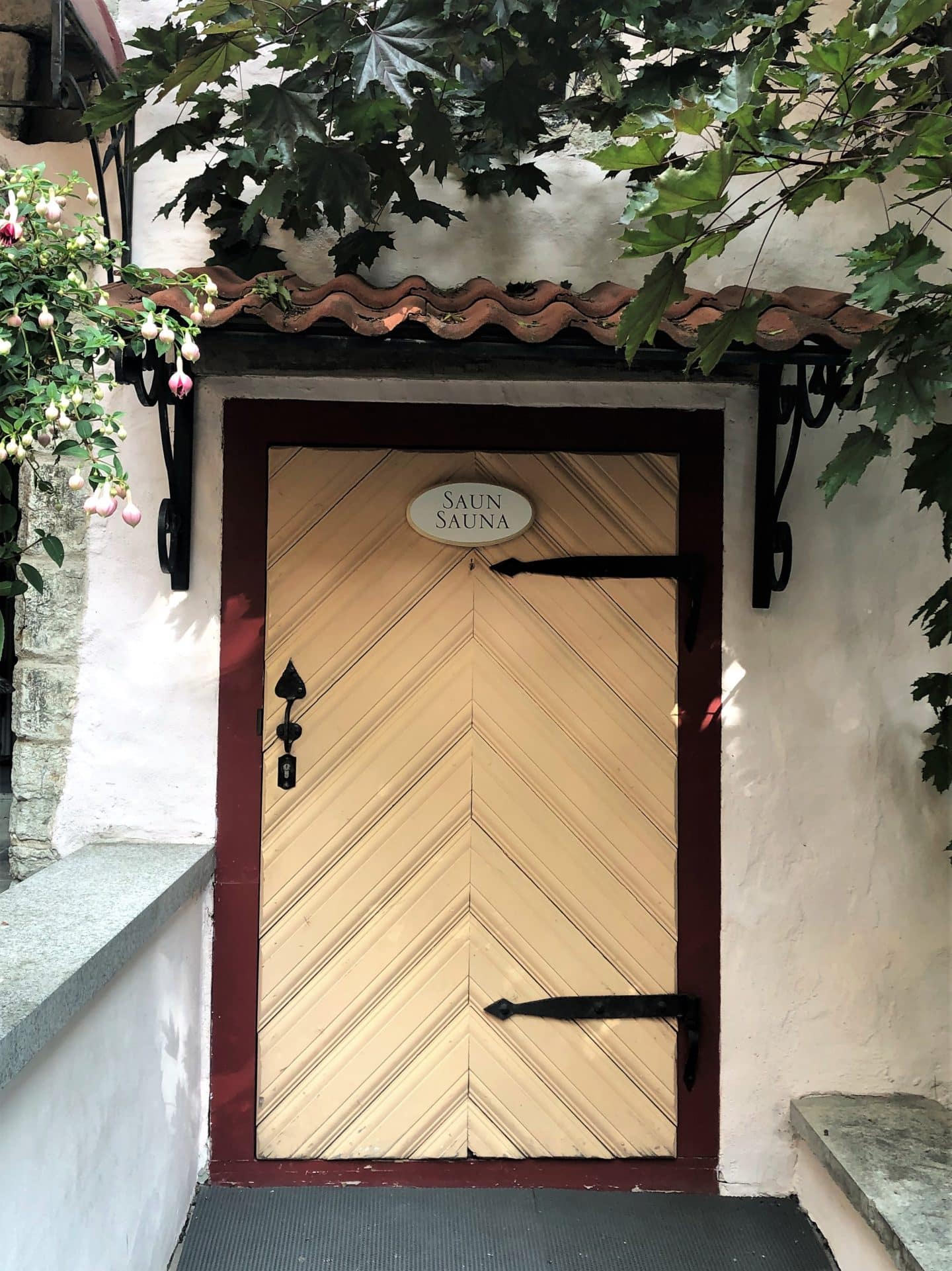 Schlossle Hotel Tallinn: The pale yellow Sauna door in the garden with a terracotta tiled roof.
