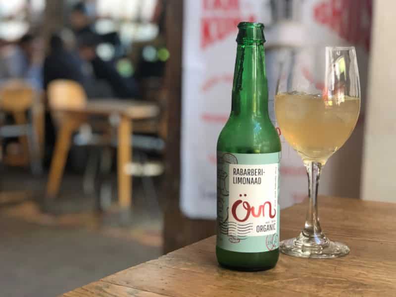 A green bottle of Rabarberi Limoonaad with a wine glass half poured with the lemonade at F-Hoone, Tallinn