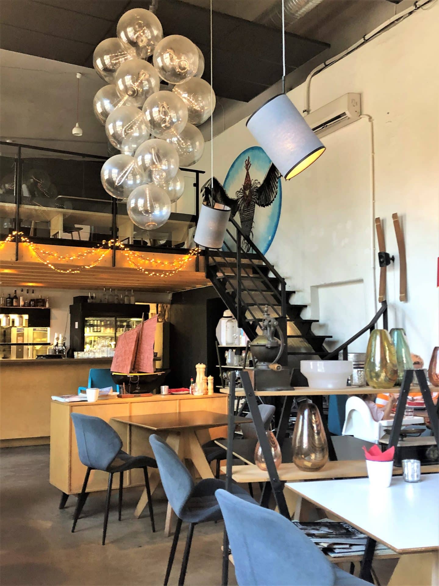 The interiors at Frenchy Bistro, Tallinn with a black staircase, blue chairs and wooden accents throughout the restaurant.