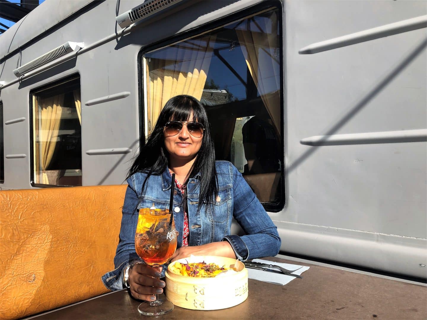 Bejal with an Aperol Spritz and fake burger with loaded fries outside at Peatus, Tallinn