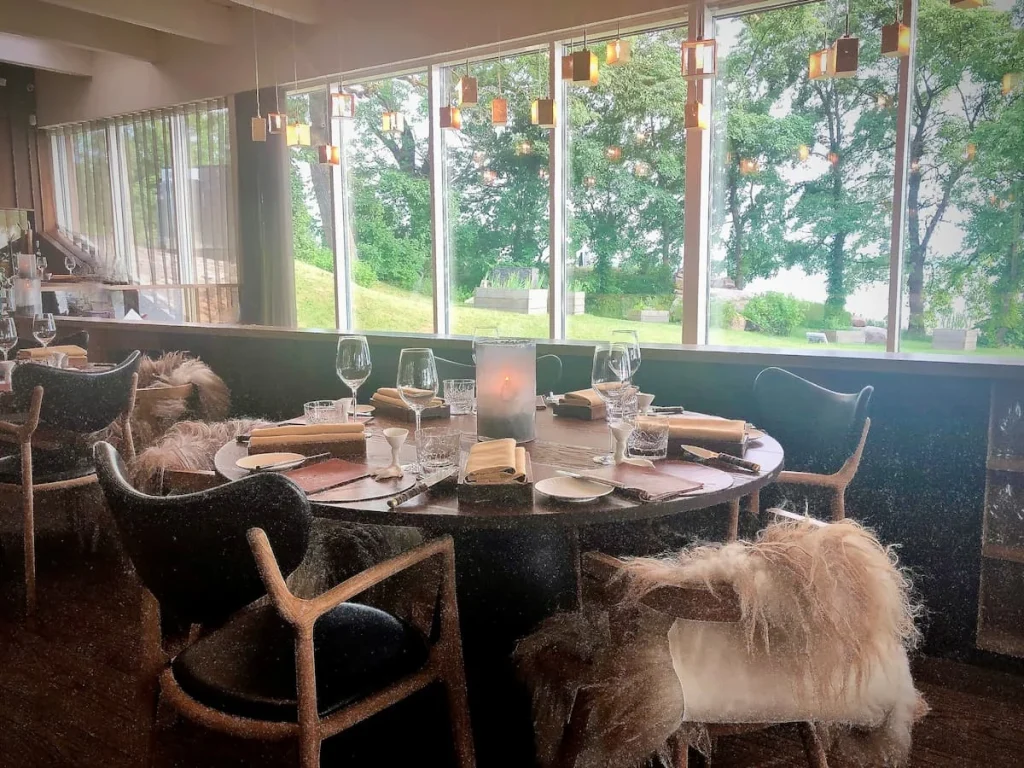 Cosy table inside Noa Chef's Hall in Tallinn with a table dressed in neutral tones, faux fur throws and views of the trees surrounding Tallinn Bay