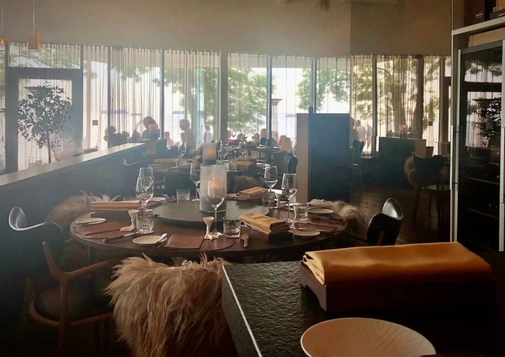 Inside Noa Chef's Hall, Tallinn with dark wood tables and chairs and cosy faux fur throws and cushions