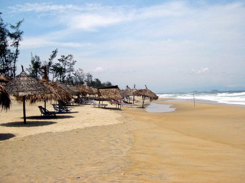 An Bang Beach, Hoi An, Vietnam. Sandy beach with wood shades and the waves crashing against the beach