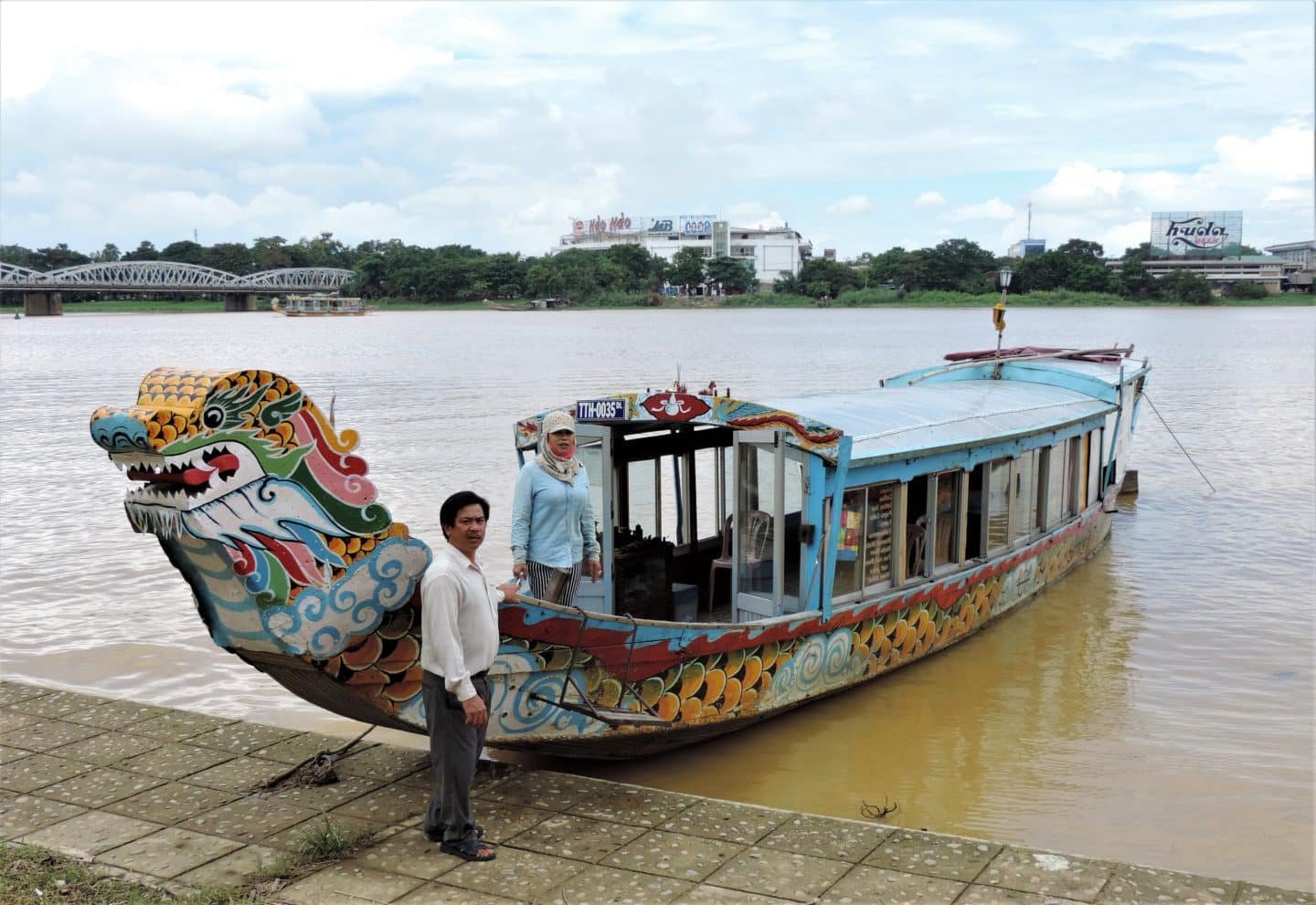 Perfume River cruise boat decorate din different colours with the river in the background and the boat crew at the front.