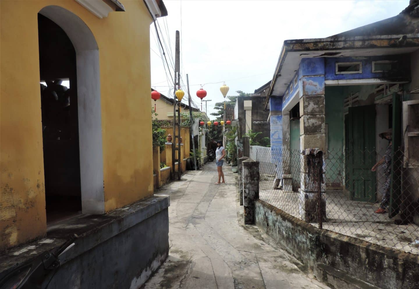 Back alleyways in Hoi An with Bejal walking down the middle and looking at camera