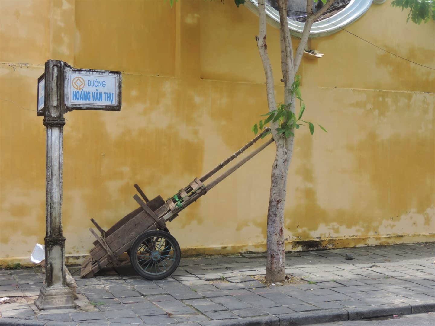 Wheel barrow with yellow wall in Hoi An's Unesco heritage centre. 