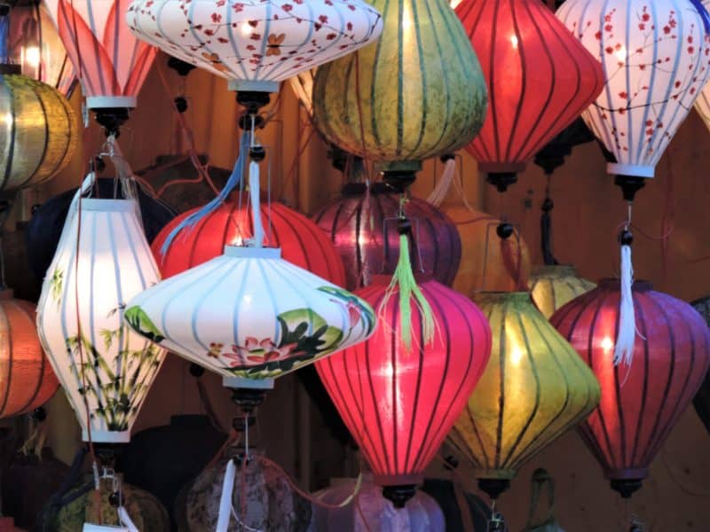 Colourful lanterns in Hoi An in different shapes and sizes hanging in a market stall.