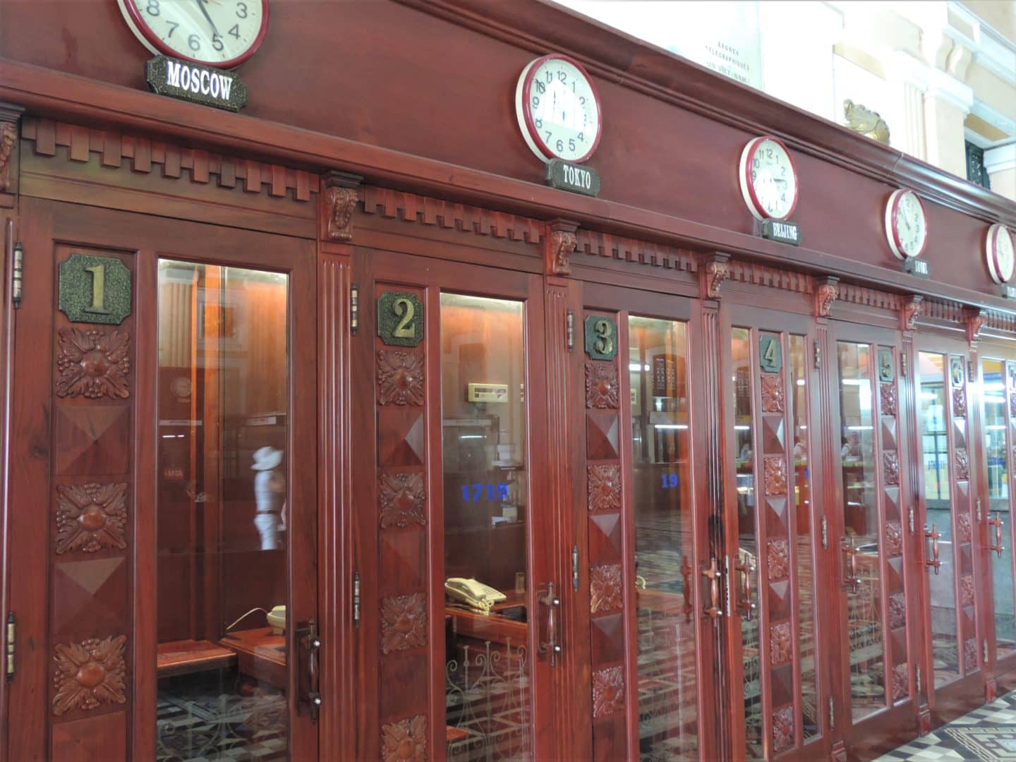 Post Office Ho Chi Minh City interior red cubicles featuring world clocks with different destinations above the individual cubicles.