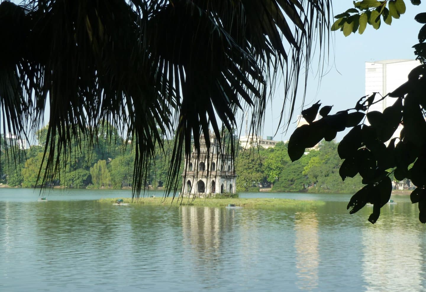 Hanoi Lake temple which is on an island in the middle of Hoan Kiem Lake. It is framed by green foliage and trees in Hanoi, Vietnam.