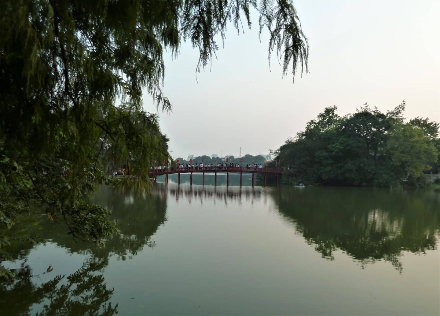 Hoan Kiem Lake with the bridge over the lake framed by trees and foliage in Hanoi, Vietnan