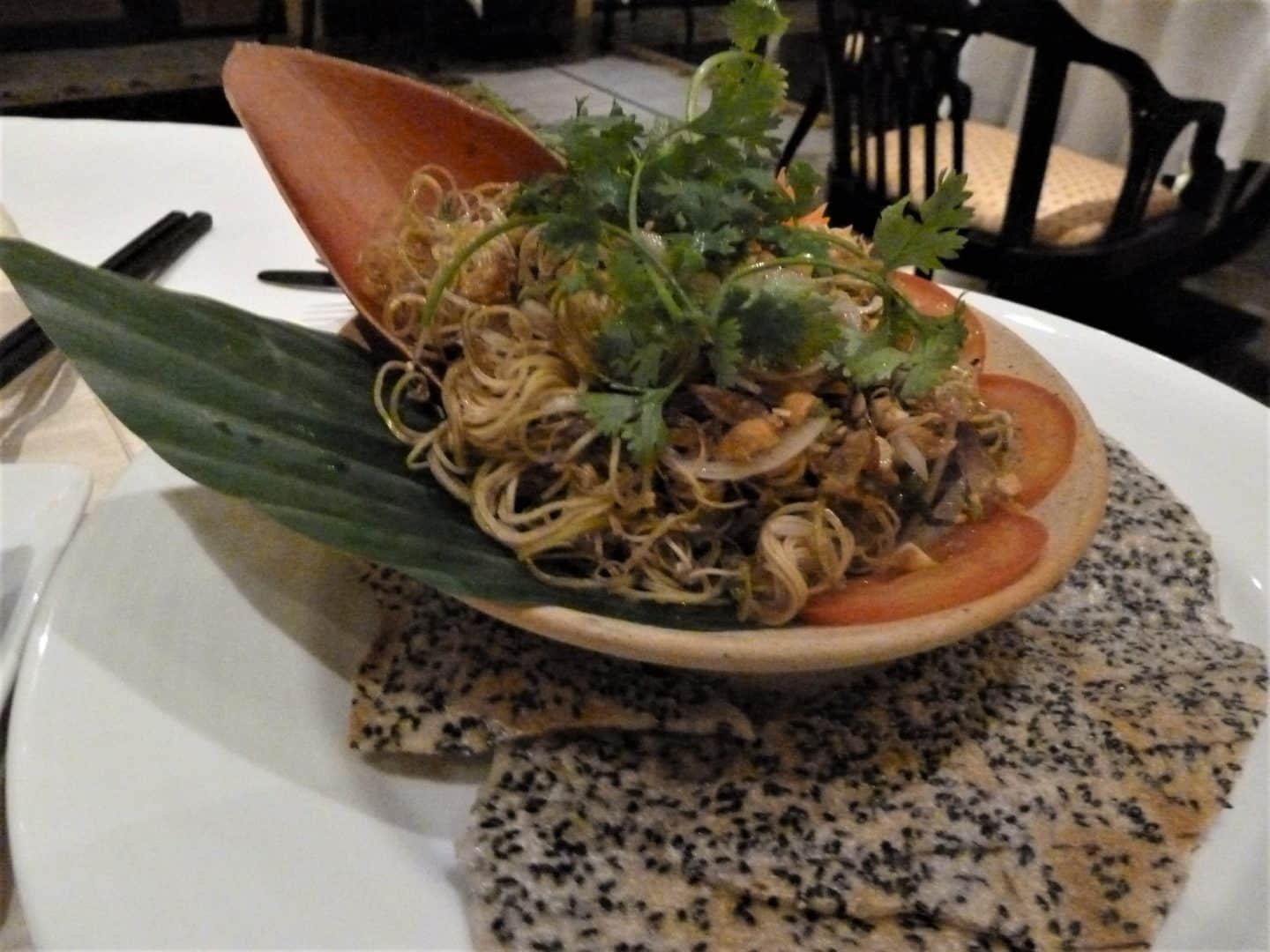 Noodles and vegeyables at La Residence Hotel & Spa in Hue. They have been placed on a leaf and dressed with green herbs and leaves on a white tablecloth. part of the Sustainable tourism in Vietnam guide
