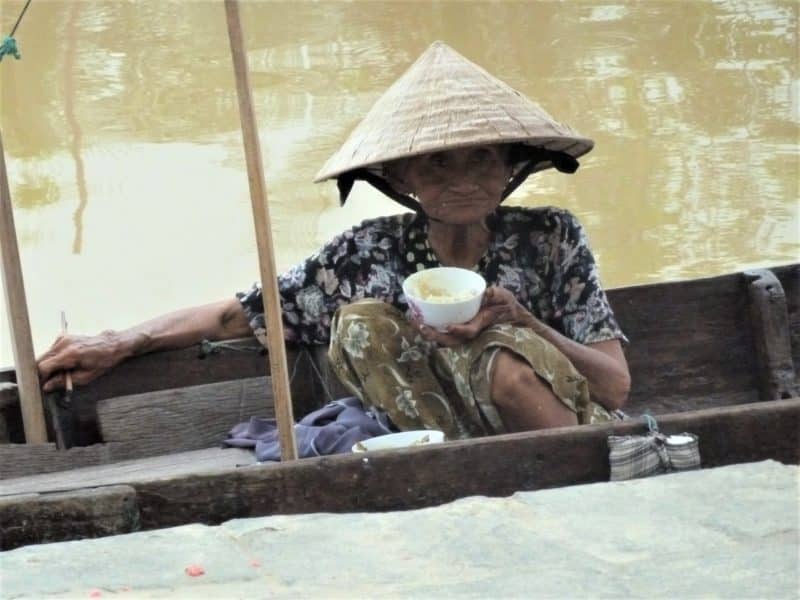 A 14 day Cultural Itinerary for Vietnam: An elderly lady sitting in a canoe with coconut in a bowl on the Mekong Delta river