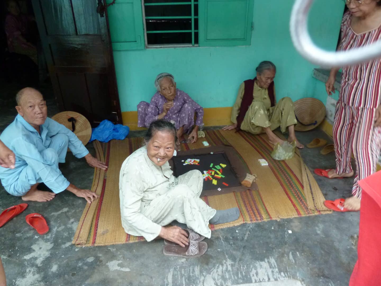 Elderly people playing draughts in Hoi An centre and posing for a photo