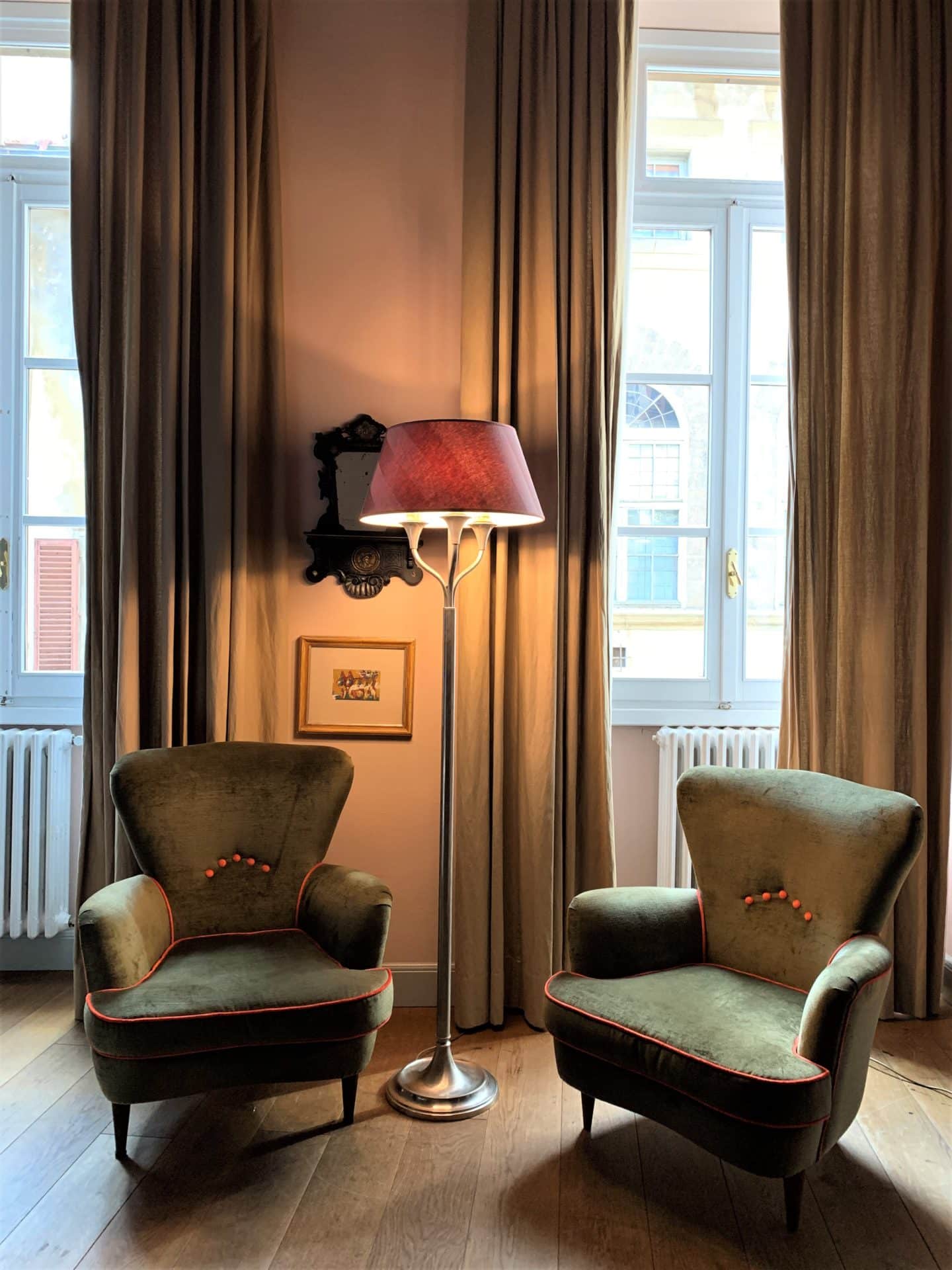 2 pink and green armchairs with dark pink floor light adn shade between them