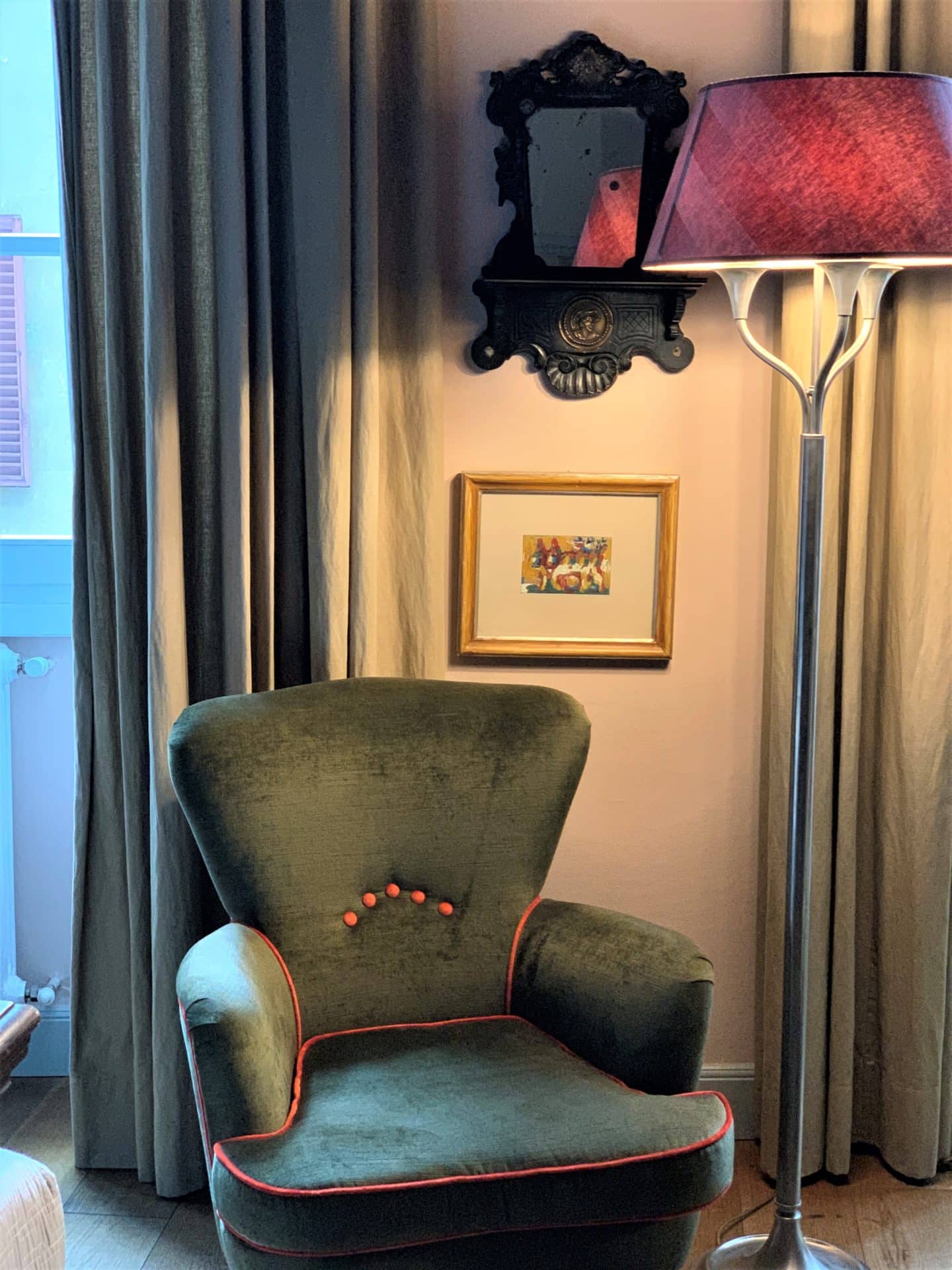 Pale green armchair with dark pink light and long curtains the background