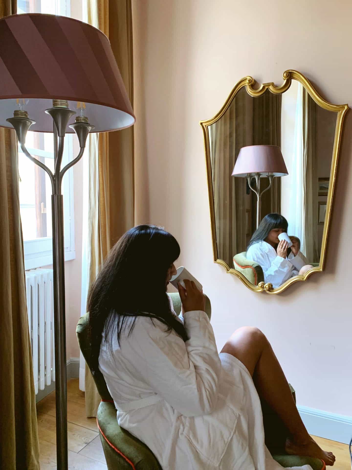 Bejal sat with a hot drink, looking into ornate mirror at Sporarno Suites