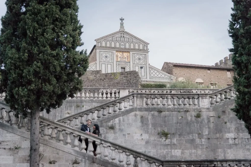  Oltrarno An Artisanal Neighbourhood in Florence: Bejal & Will standing on stairs outside San Miniato al Monte church in Florence