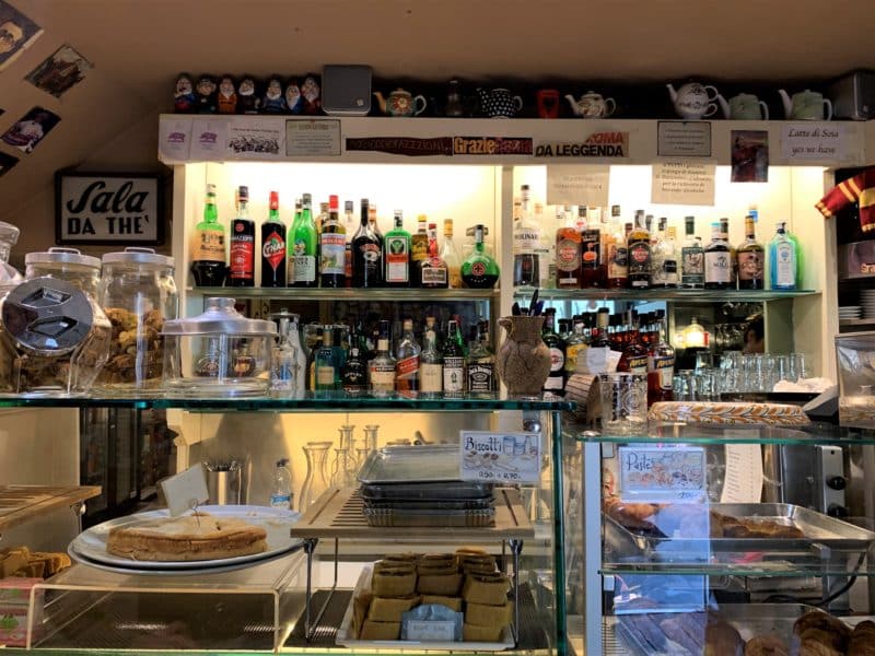 Vegetarian food in Florence. The counter of Caffè degli Artigiani with cajes, coffees and bottles of alcohol on the shelf behind.