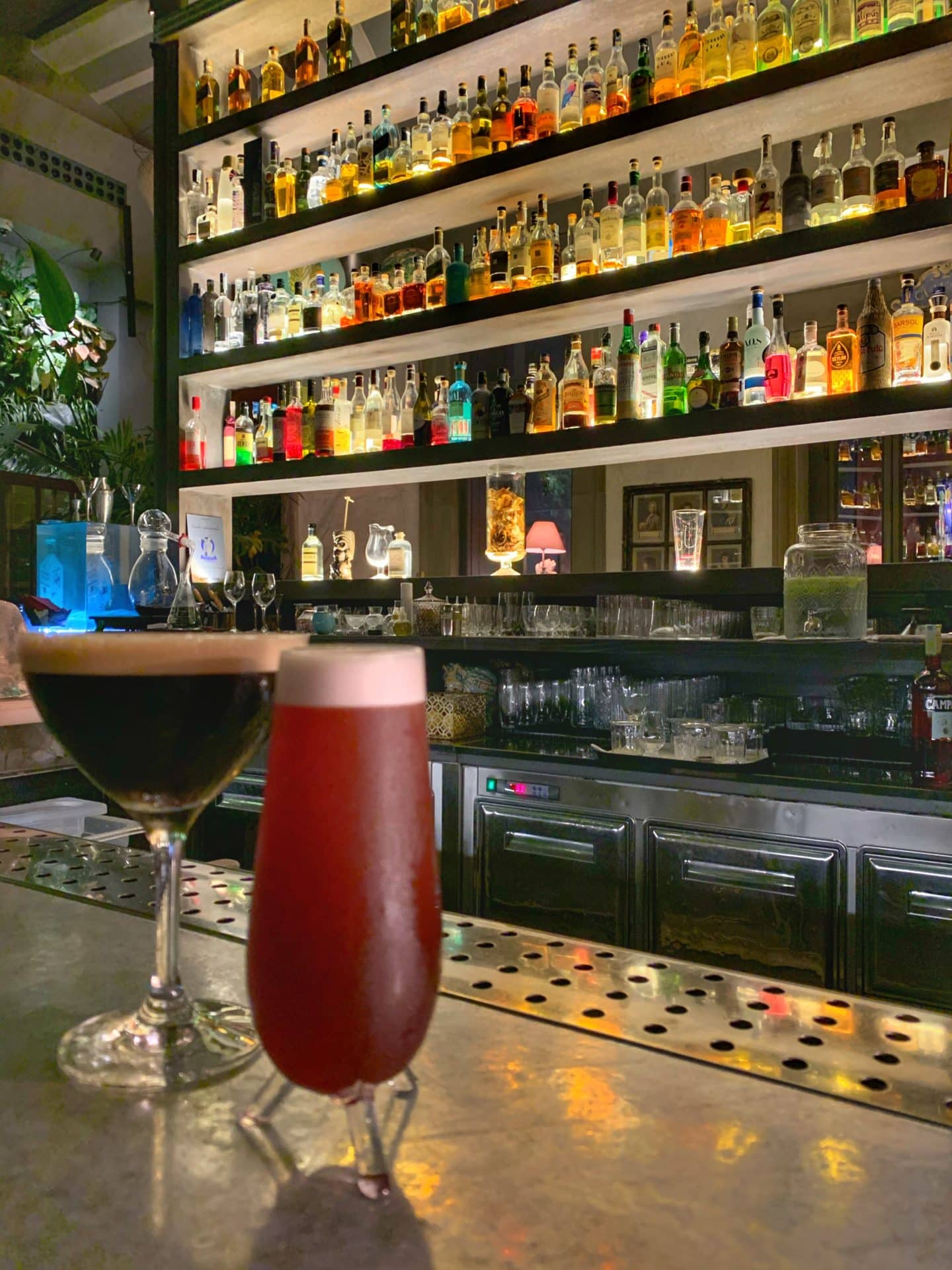 Il Locale - An Espresso Martini and red coloured cocktail with the alcohol bottles of the bar in the background in Florence.