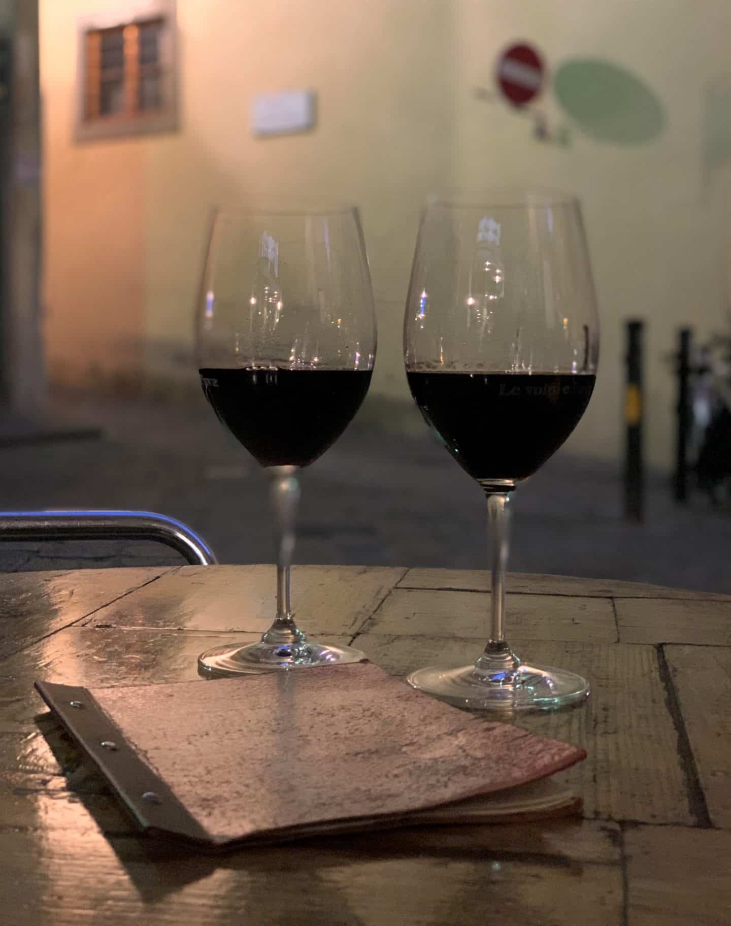 Le Volpi E L'uva - 2 red wine glasses on a wooden table.