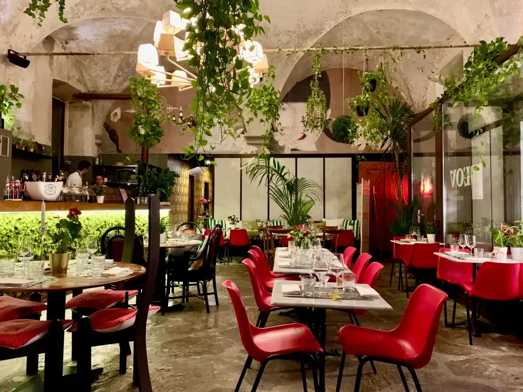 Vegetarian-friendly food in Florence. Th einteriors of green foliage and red seating at L'OV restaurant.
