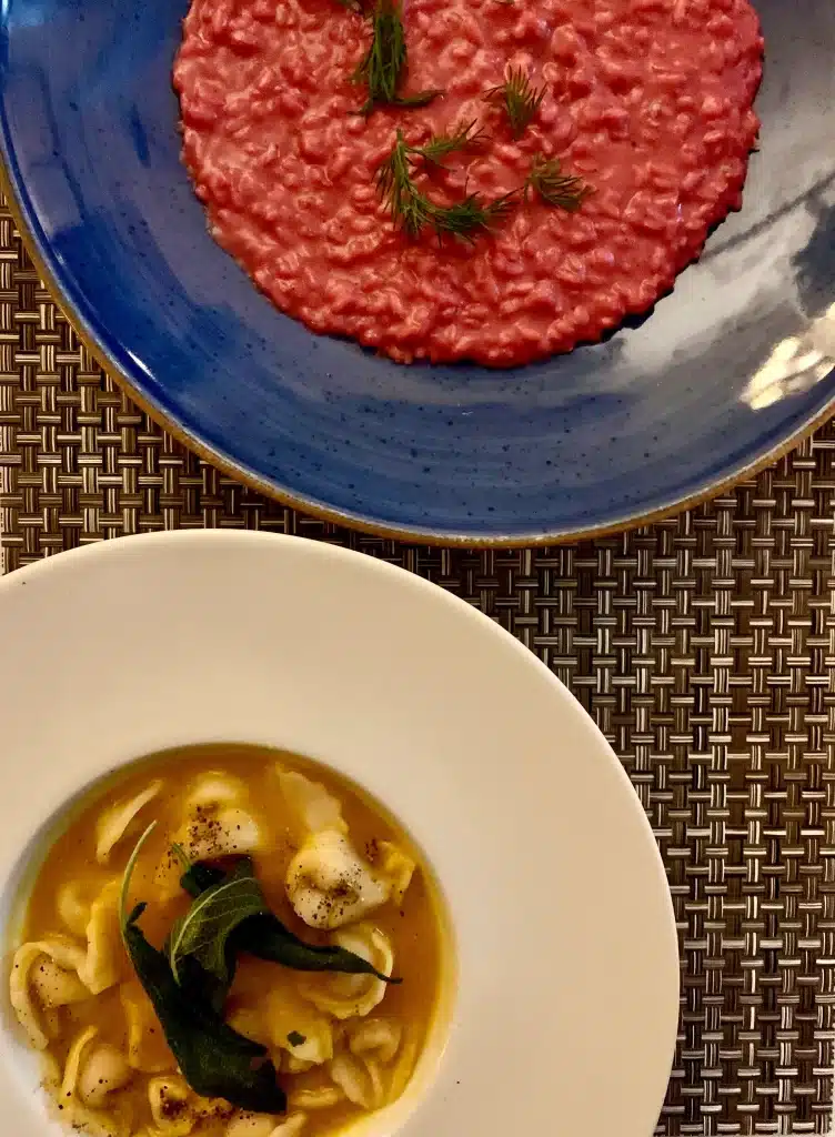 Vegetarian-friendly food in Florence, beetroot pink risotto and ravioli in a yellow sauce.