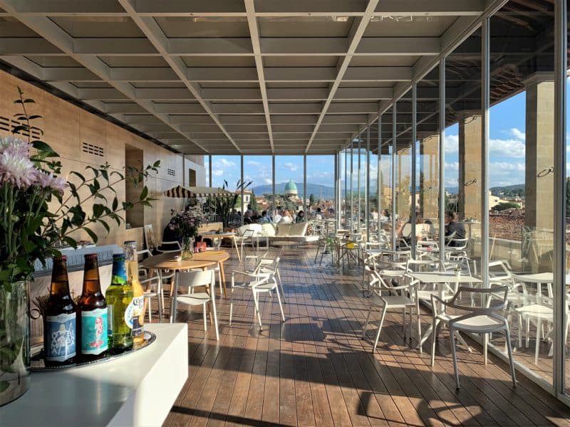 The interiors of the Caffè del Verone. Tables and chairs with glass windows behind with view sof the surroundings.