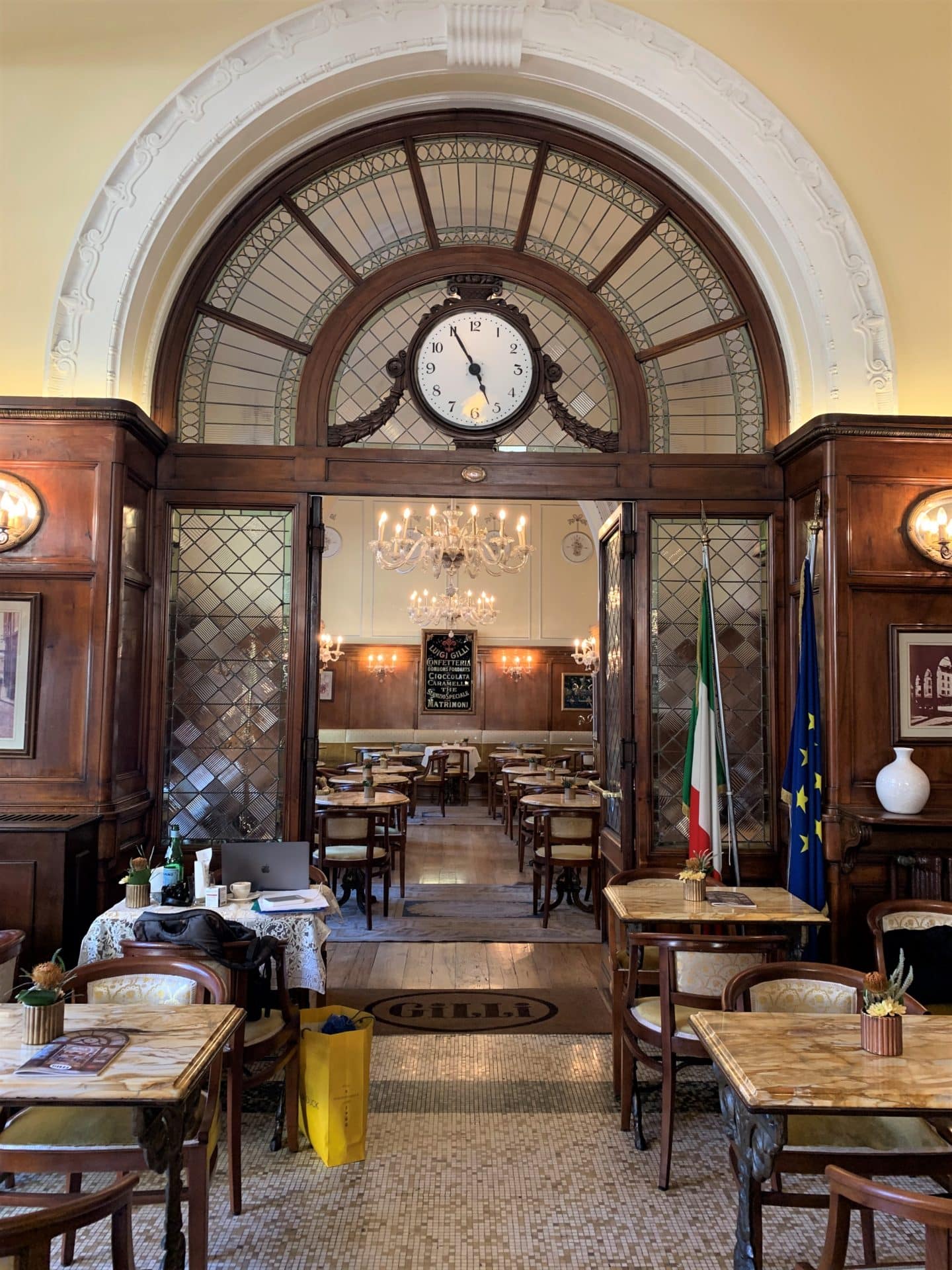 Vegetarian-friendly food in Florence. The interior of Caffè Gilli with a chandelier in the middle of the ceiling with cream and brown tables and chairs 