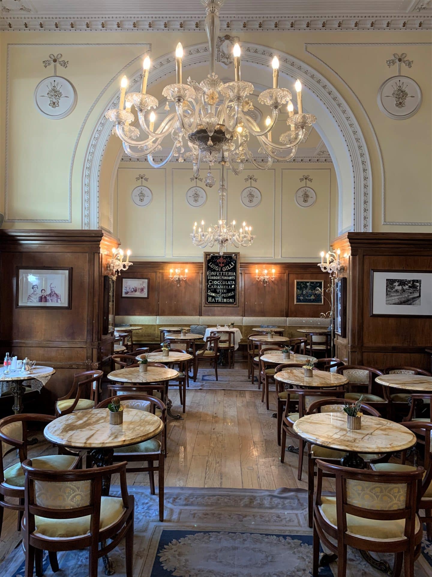 Vegetarian-friendly food in Florence. The interior of Caffè Gilli with a chandelier in the middle of the ceiling with cream and brown tables and chairs 