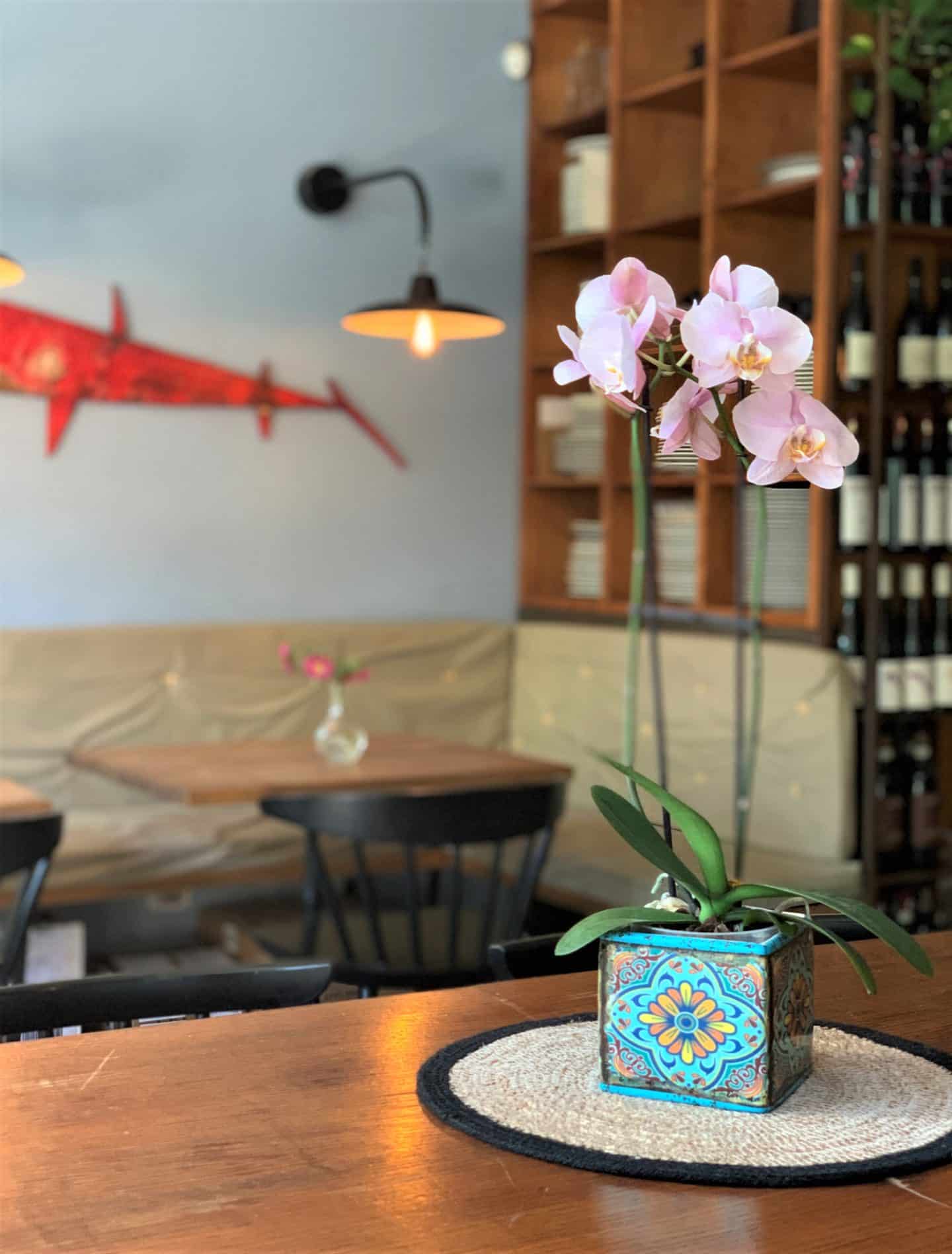 Santarosa Bistrot vase on table with flowers and a black light in the back.
