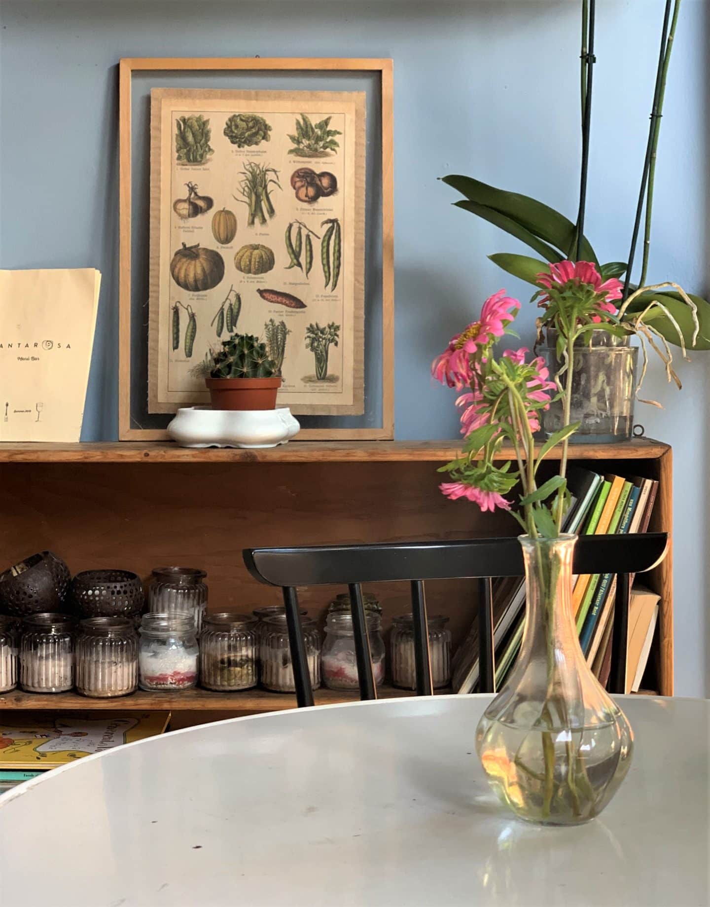 Santarosa Bistrot vase on table with flowers and a framed photo in the back. 