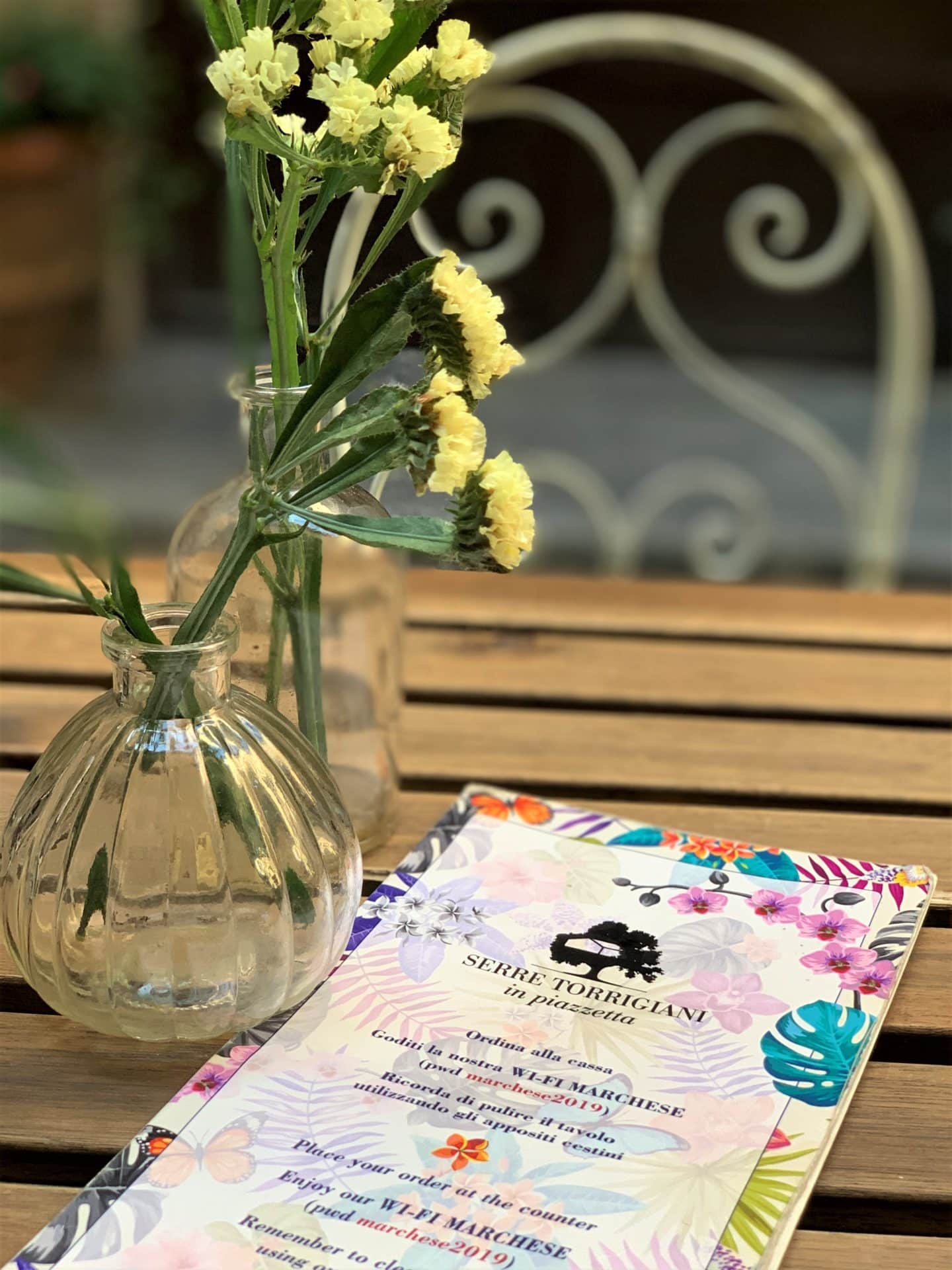 Serre Torrigiani in Piazzetta - drinks menu with a small vase with yellow carnations. 