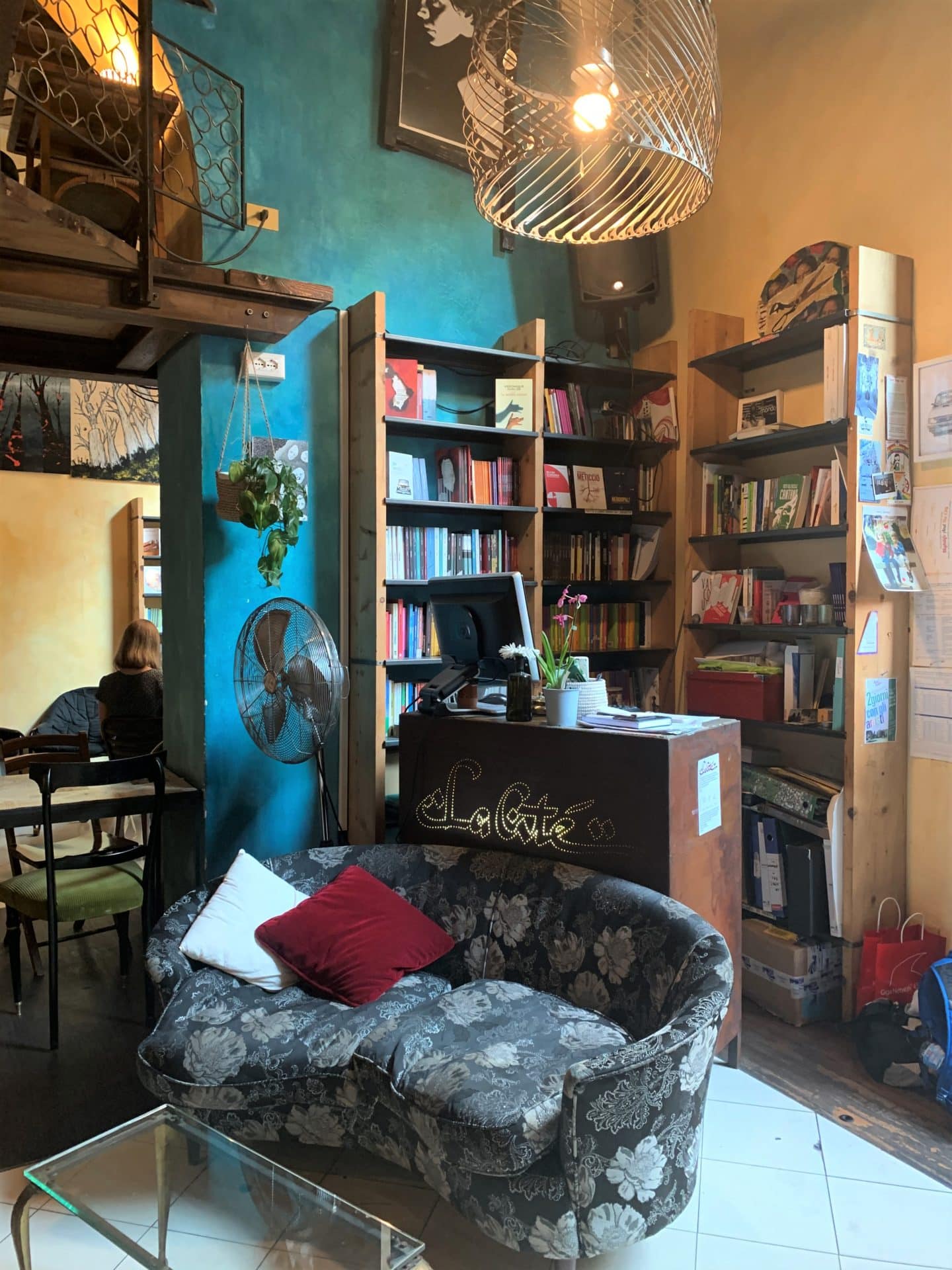 Libreria Cafè La Cité rooms with a floral sofa, teal and mustard yellow walls 
