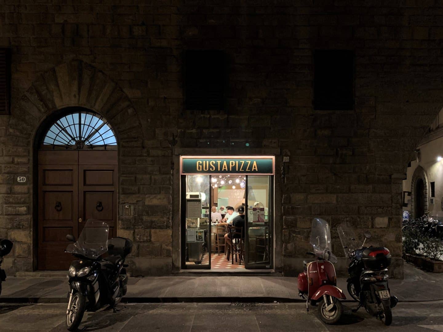 Gista Pizza exterior with motorbikes outside, taken in the dark