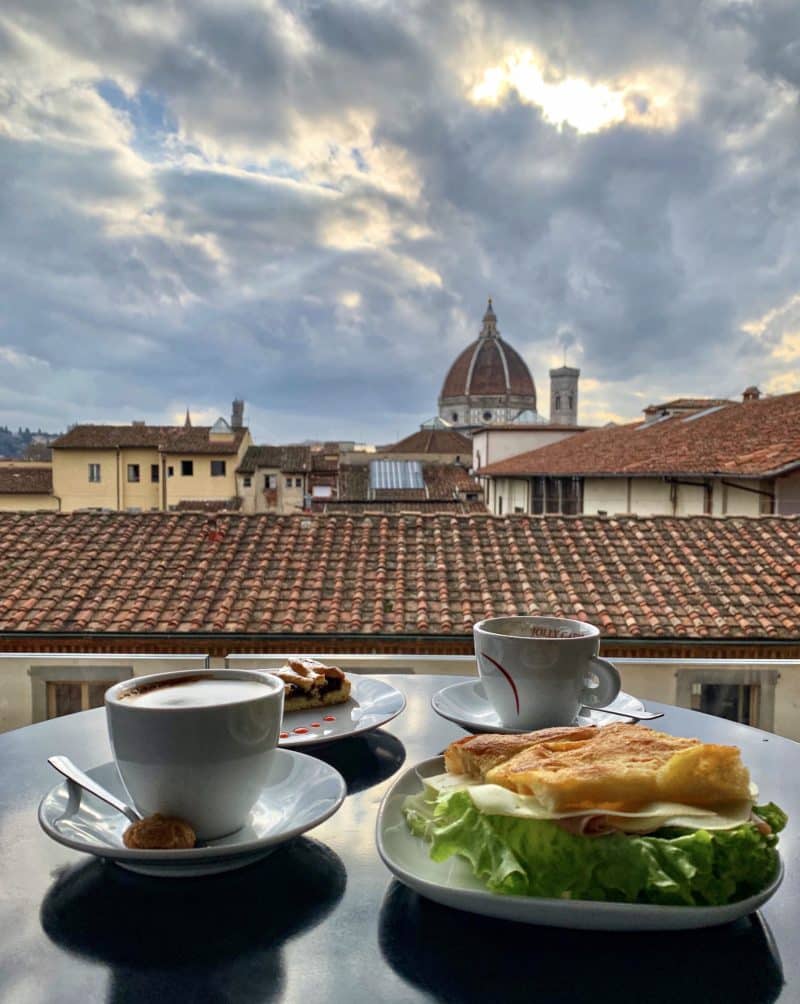 The views of the duomo out of the windows of Caffè del Verone. A cup of coffee frames the picture with a focaccia sandwich
