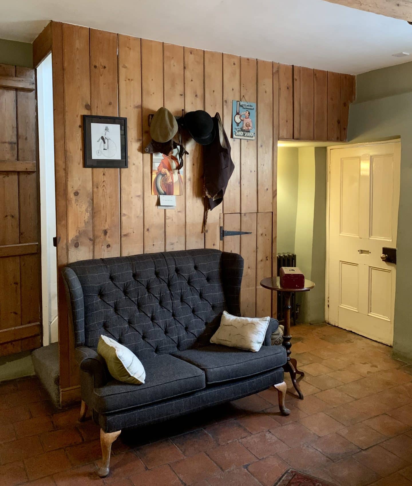 Michelin Star dining at John's House in Leicestershire: a navy blue 2 seat sofa in the lounge area with a wooden panelled wall.
