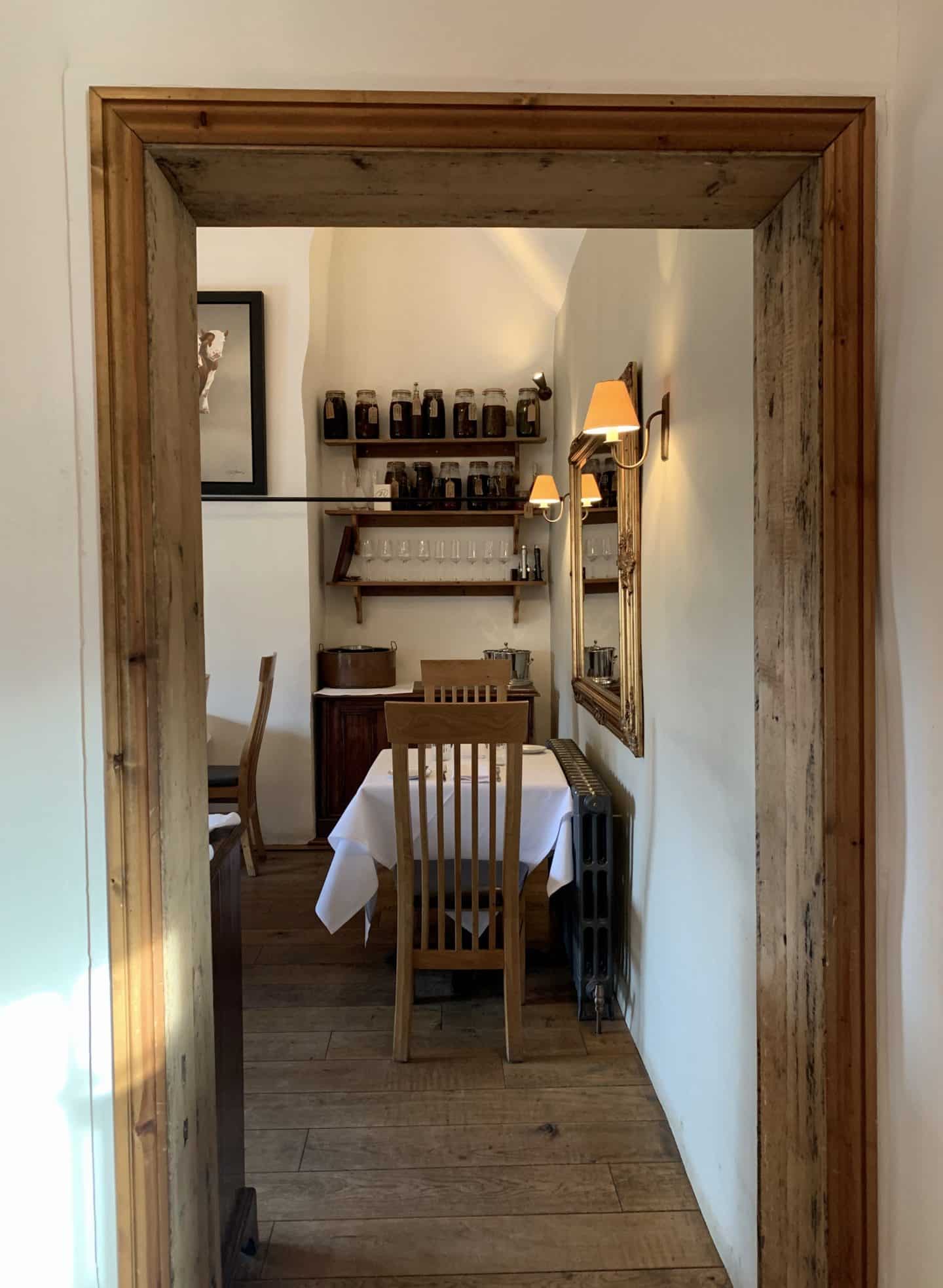 The view into another dining room from the larger room. A table of 2 has been set up. 