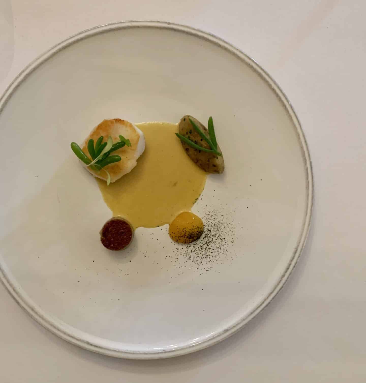 The Taster Menu at Michelin-Starred, A flat lay of the Lightly Salted Fillet of Cod, Brawn, Aubergine, Passion Fruit and Curry Spices. 