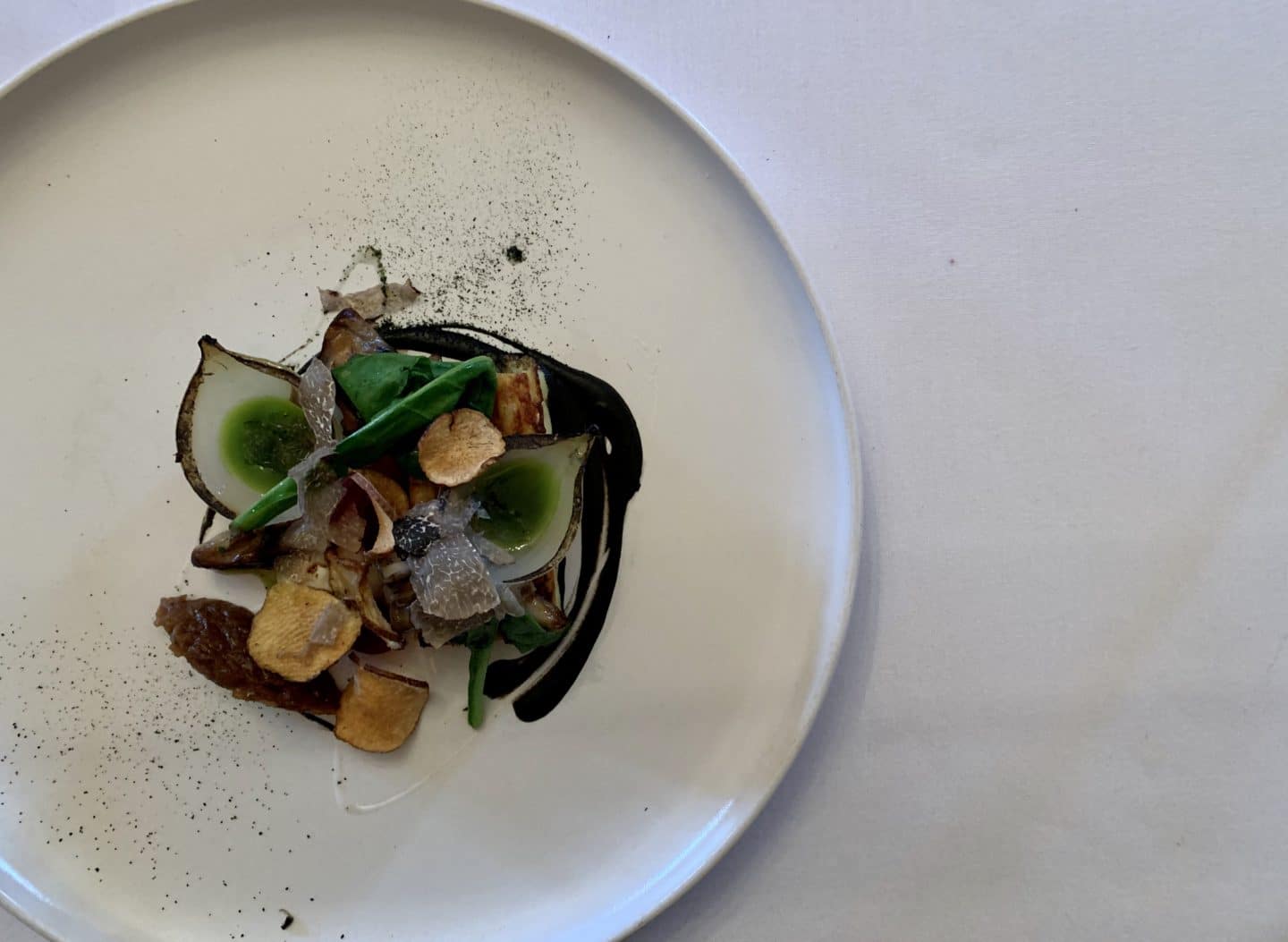 A flat lay of a white plate containing the Truffle Pudding, Hen of the Woods, Artichoke and Chilli 