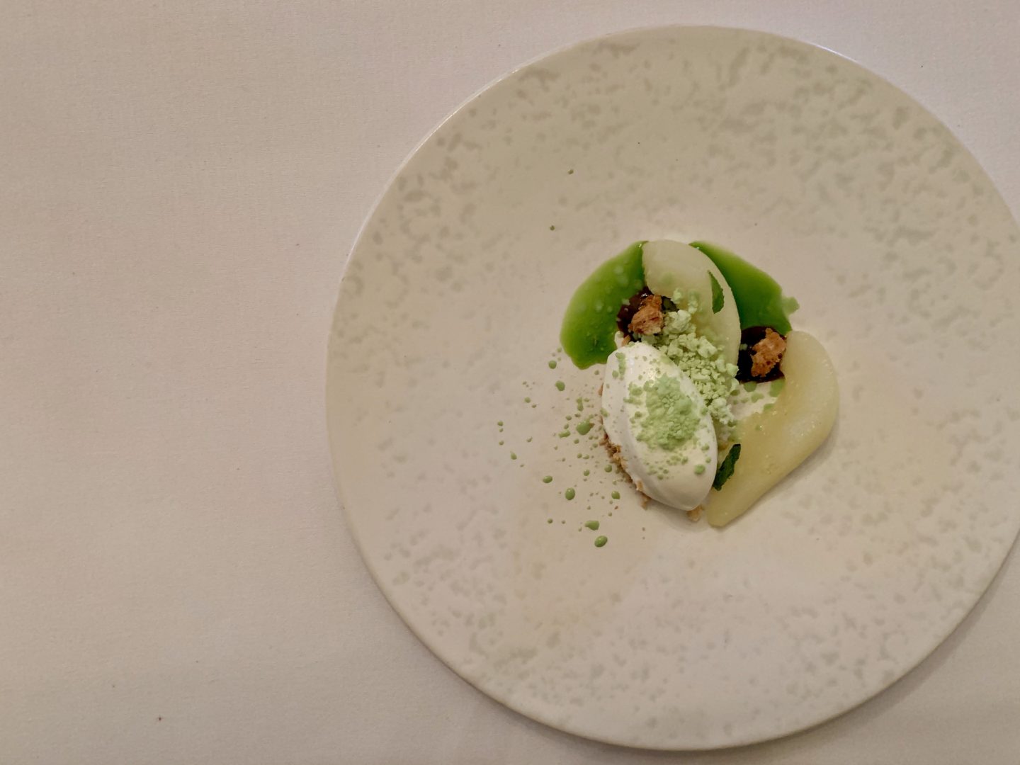 Flat lay of a white plate with Poached Pears, Liquorice, Sweet Cheese, Mint and Hazelnut l