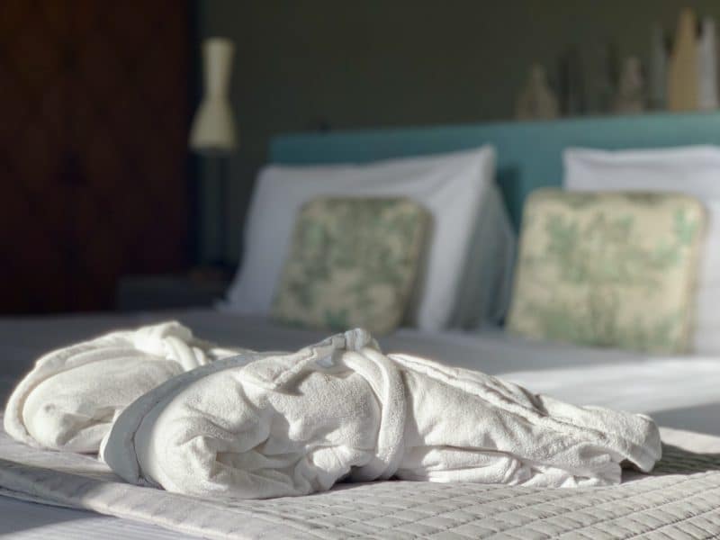 Bed with 2 white fluffy bathrooms on top