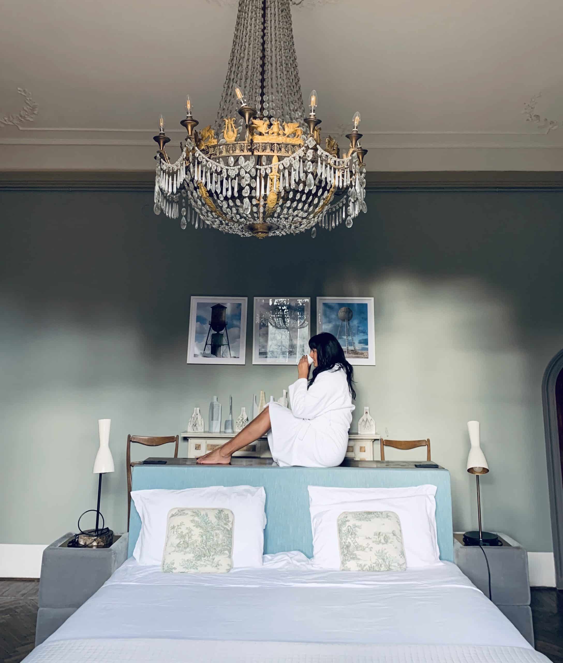 Bejal sat on bed ledge having a coffee