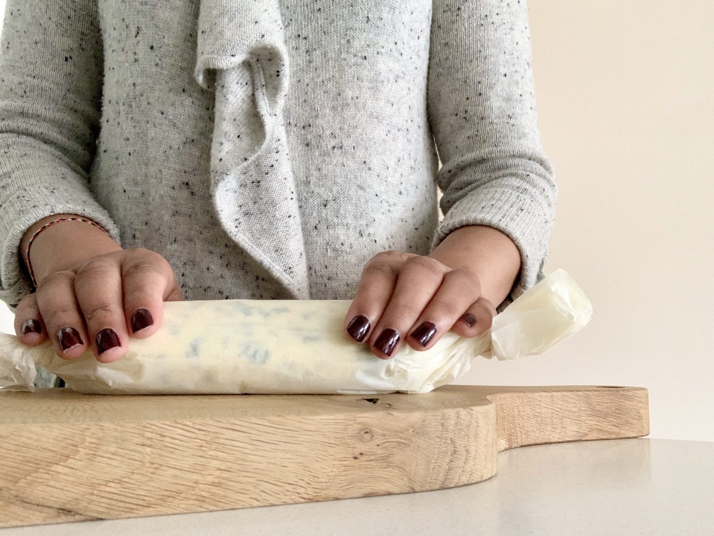 Melted butter, chives and salt mix on greaseproof paper being rolled into a sausage shape by Bejal, ready for refrigerating