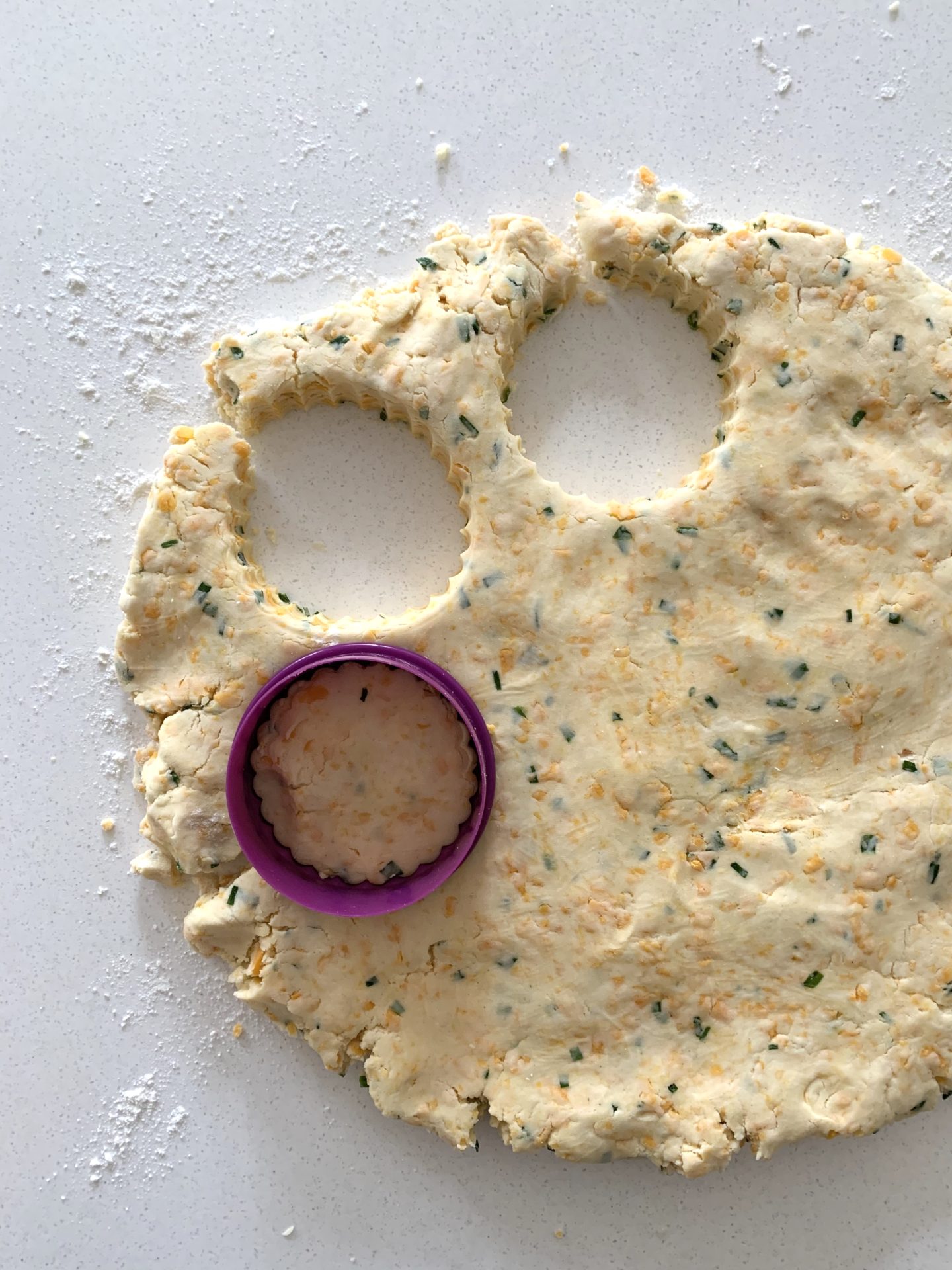 Red Leicester cheese scones mix rolled out with cutter over the top cutting out scone shapes