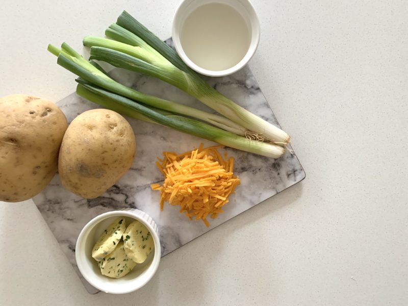 grey and white marble effect mat with grated Red Leicester cheese, potato, garlic and herd butter and spring onions