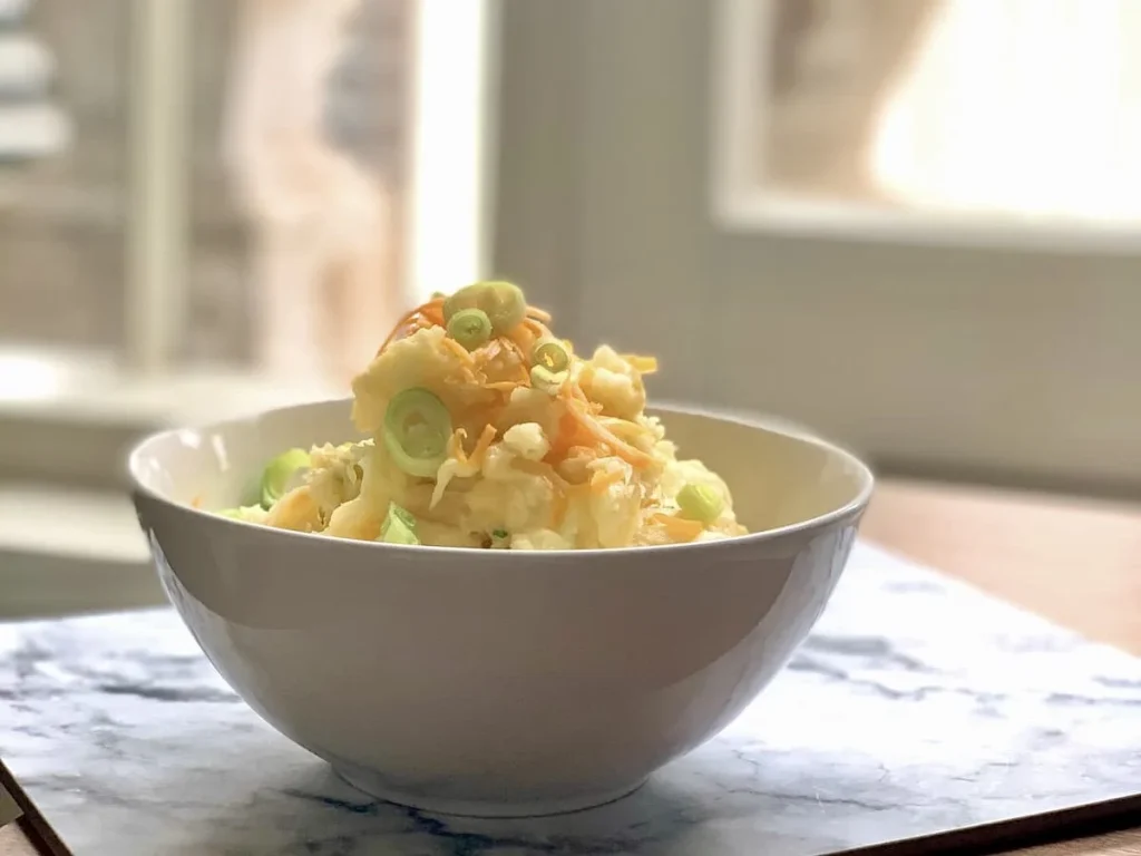 Red Leicester Cheese mash topped with spring onions on a grey and white marble effect mat