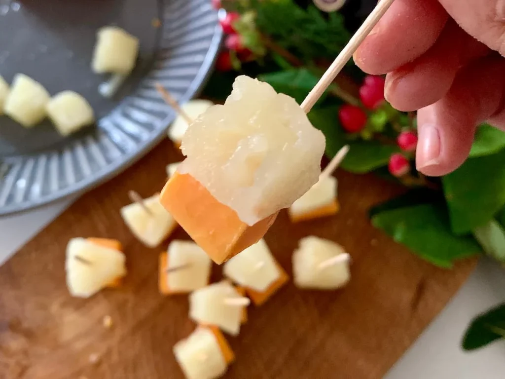 Red Leicester cheese and pineapple stick close-up with more in the background for a party.