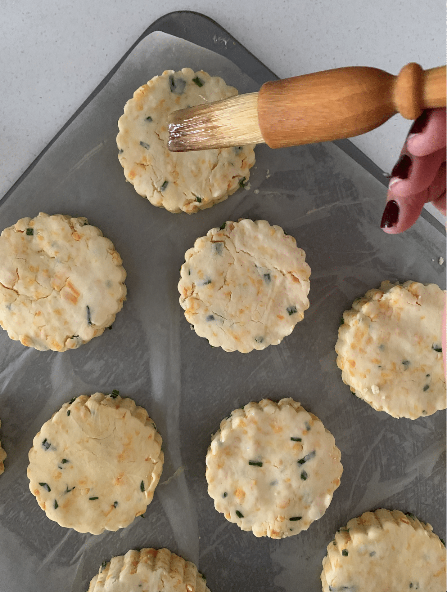 Bejal egg washing the scones with a brown brush